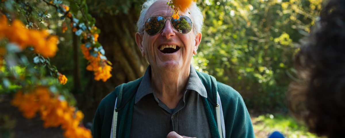 older man laughs amongst autumnal coloured trees