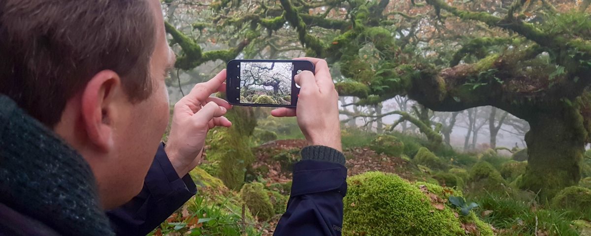 man gathering stories filming in Dartmoor with smartphone